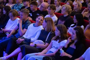 Zdjęcie przedstawia: uśmiechniętą publiczność.