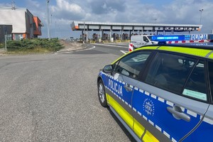 zdjęcie przedstawia radiowóz z załączonymi światłami błyskowymi na tle autostrady