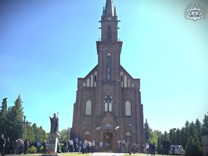 zdjęcie przedstawia przybyłych na uroczystość żałobną gości na tle kościoła
