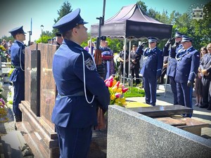 zdjęcie przedstawia policjantów asysty honorowej oraz oficerów policji, którzy oddają honory na cmentarzu