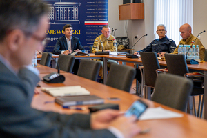 na zdjęciu osoby przy stole, wśród których znajduje się policjant i strażacy