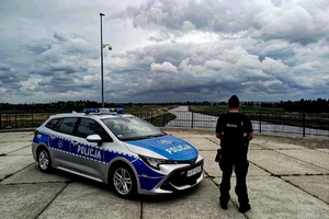 na zdjęciu policjant przy radiowozie na moście nad rzeką