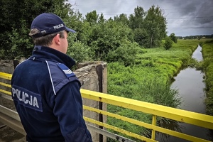 na zdjęciu policjant na moście przy potoku