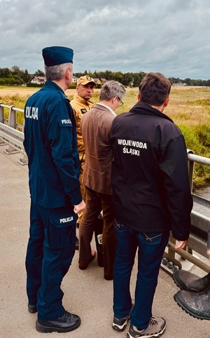 Zdjęcie przedstawia policjanta oraz Wojewodę Śląskiego podczas oględzin terenów narażonych na wylewanie rzek.
