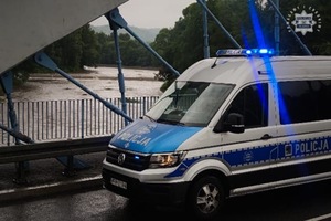 Zdjęcie przedstawia stojący na moście oznakowany radiowóz policyjny typu furgon.