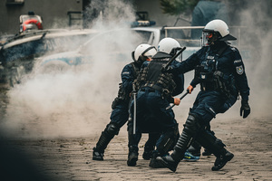 na zdjęciu policjanci z pałkami w rękach