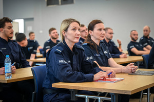 na zdjęciu policjanci i policjantki siedzący w ławkach