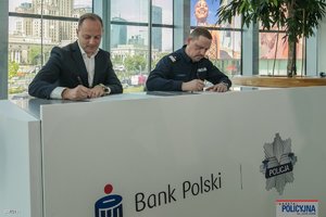 na zdjęciu komendant główny i przedstawiciel banku w trakcie podpisywania dokumentów