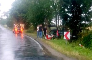 na zdjęciu osoby przy rozbitym samochodzie w rowie