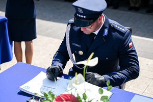 kolorowe zdjęcie przedstawiające policjanta składającego podpis na dokumencie