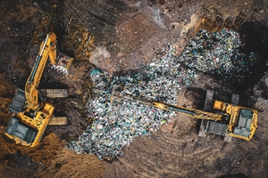 Ujęcie z drona, przedstawia dużą ilość śmieci i pracujące koparki