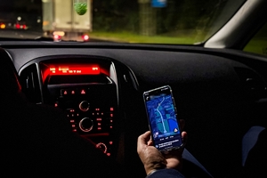 Zdjęcie jest wykonane we wnętrzu samochodu, widać na nim włączoną w telefonie nawigację