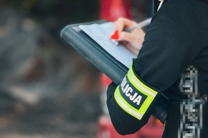 Na zdjęciu osoba wypełniająca dokumentacje z opaska z napisem policja