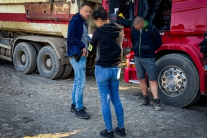 Zdjęcie przedstawia nieumundurowanych policjantów przy tirze z zatrzymanym mężczyzną