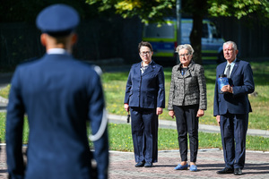 Na zdjęciu znajdują się zaproszeni goście, a w tle znajduje się odwrócony plecami funkcjonariusz Policji.