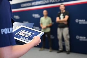 policjant trzyma  uroczyste podziękowania dla mężczyzn za ich bohaterski czyn
