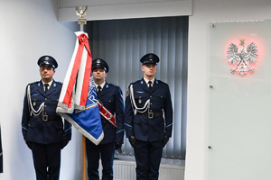 Fotografia przedstawia trzech umundurowanych funkcjonariuszy Policji wchodzących w skład pocztu sztandarowego