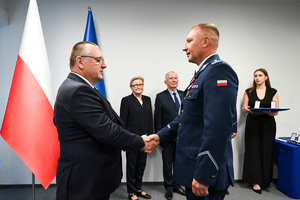 Zdjęcie przedstawia umundurowanego funkcjonariusza Policji oraz gości.