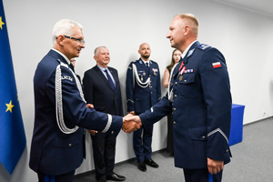 Zdjęcie przedstawia umundurowanych funkcjonariusz Policji w tym Komendanta Wojewódzkiego Policji w Katowicach - nadinsp. Mariusza Krzystyniaka, który gratuluje mundurowemu
