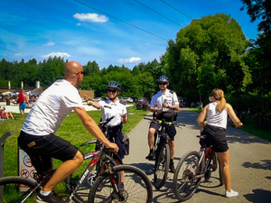 Na kolorowym zdjęciu widoczny patrol Policji Nieetatowej Grupy Rowerowej wraz dwoma rowerzystami
