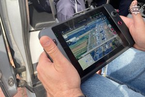 Na kolorowym zdjęciu widoczny policjant obsługujący bezzałogowy statek powietrzy &quot;dron&quot;