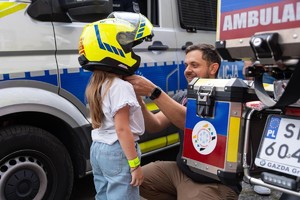 Na kolorowym zdjęciu widać 6-letnią Oliwię, w tle radiowóz i motoambulans