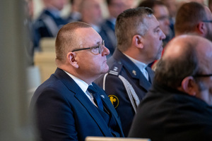 mężczyzna w garniturze siedzi w ławie kościelnej
