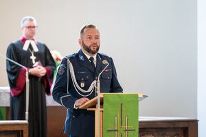 policjant w mundurze galowym stoi przy mównicy
