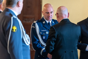 policjanci w mundurach galowych rozmawiają z mężczyzną w garniturze