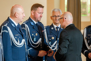 policjanci w mundurach galowych rozmawiają z mężczyzną w garniturze