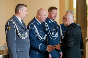 policjanci w mundurach galowych rozmawiają z mężczyzną w garniturze