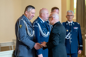 policjanci w mundurach galowych rozmawiają z mężczyzną w garniturze
