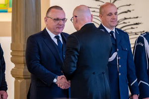 mężczyzna w garniturze wręcza medal innemu mężczyźnie w garniturze