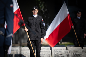 uczennica z klasy mundurowej stoi z biało czerwoną flagą