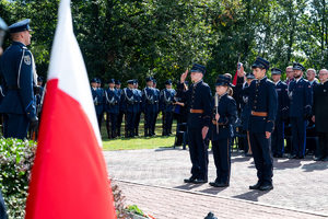 młodzież ubrana w historyczne mundury salutuje przy pomniku