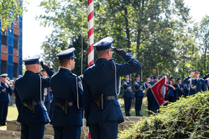policjanci w strojach galowych wciągają flagę na maszt