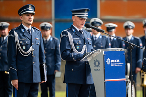 policjant w mundurze galowym stoi  przy mównicy