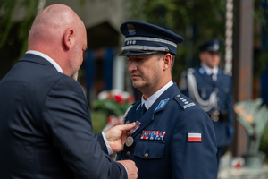 mężczyzna w garniturze wręcza medal policjantowi