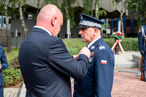 mężczyzna w garniturze wręcza medal komendantowi