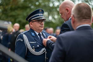 mężczyzna w garniturze przypina medal policjantowi