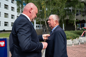 mężczyzna w garniturze wręcza medal innemu mężczyźnie