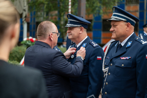 mężczyzna w garniturze przypina medal policjantowi
