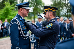 strażnik miejski przypina medal komendantowi w mundurze galowym