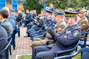 mundurowi siedzą na krzesłach i biją brawo
