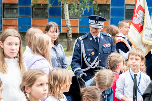 Generał Policji w mundurze galowym wraz z dziećmi przed budynkiem komendy