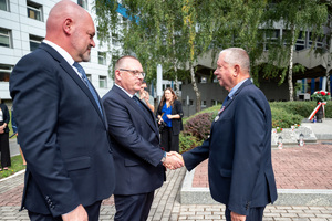 mężczyźni w garniturach wręczają medal innemu mężczyźnie w garniturze