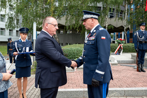 komendant w mundurze galowym podaję rękę mężczyźnie w garniturze