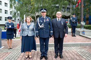 komendant w mundurze galowym stoi wspólnie z kobietą i mężczyzną w garniturze