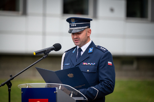 policjant w mundurze galowym stoi przy mównicy
