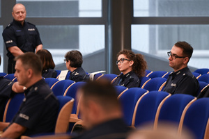 umundurowani policjanci i policjantki siedzą na krzesłach w auli
